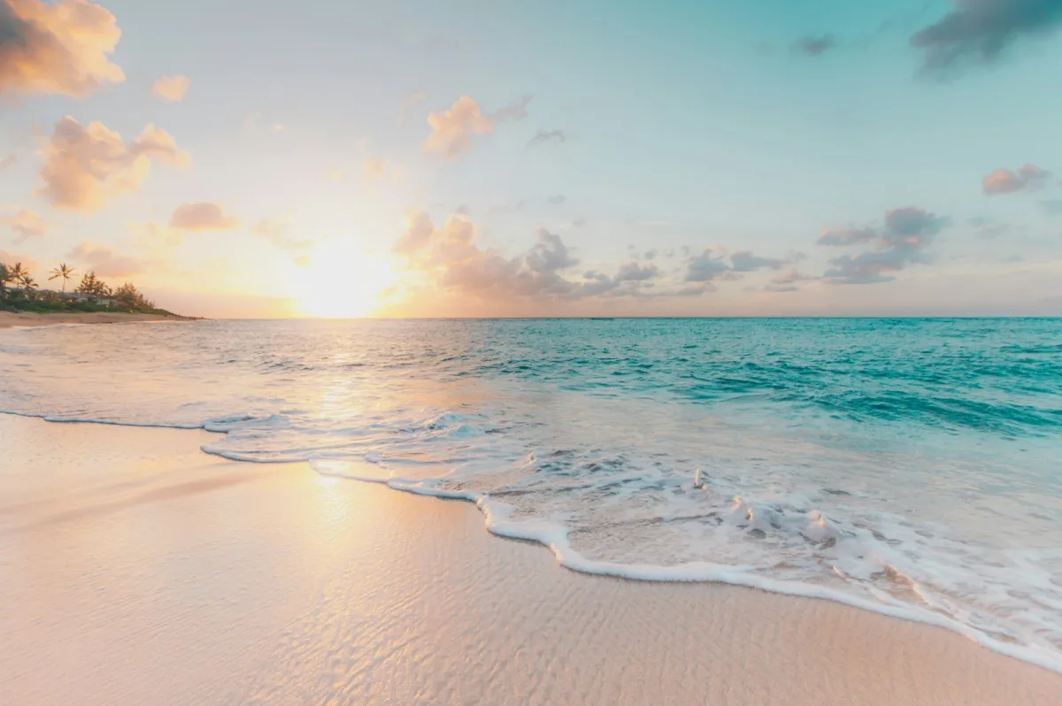 Praia com mar turquesa ao p&ocirc;r do sol